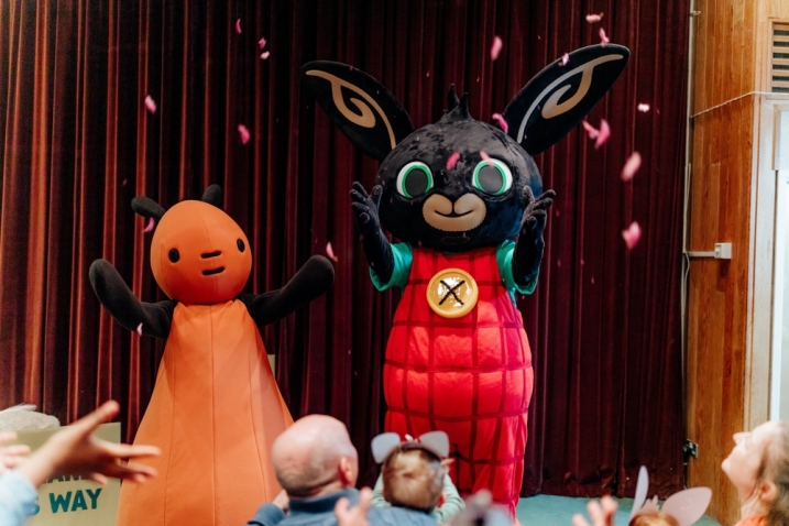 Bing and Flop characters stand on a stage for a mini-show. They are throwing petals at the audience